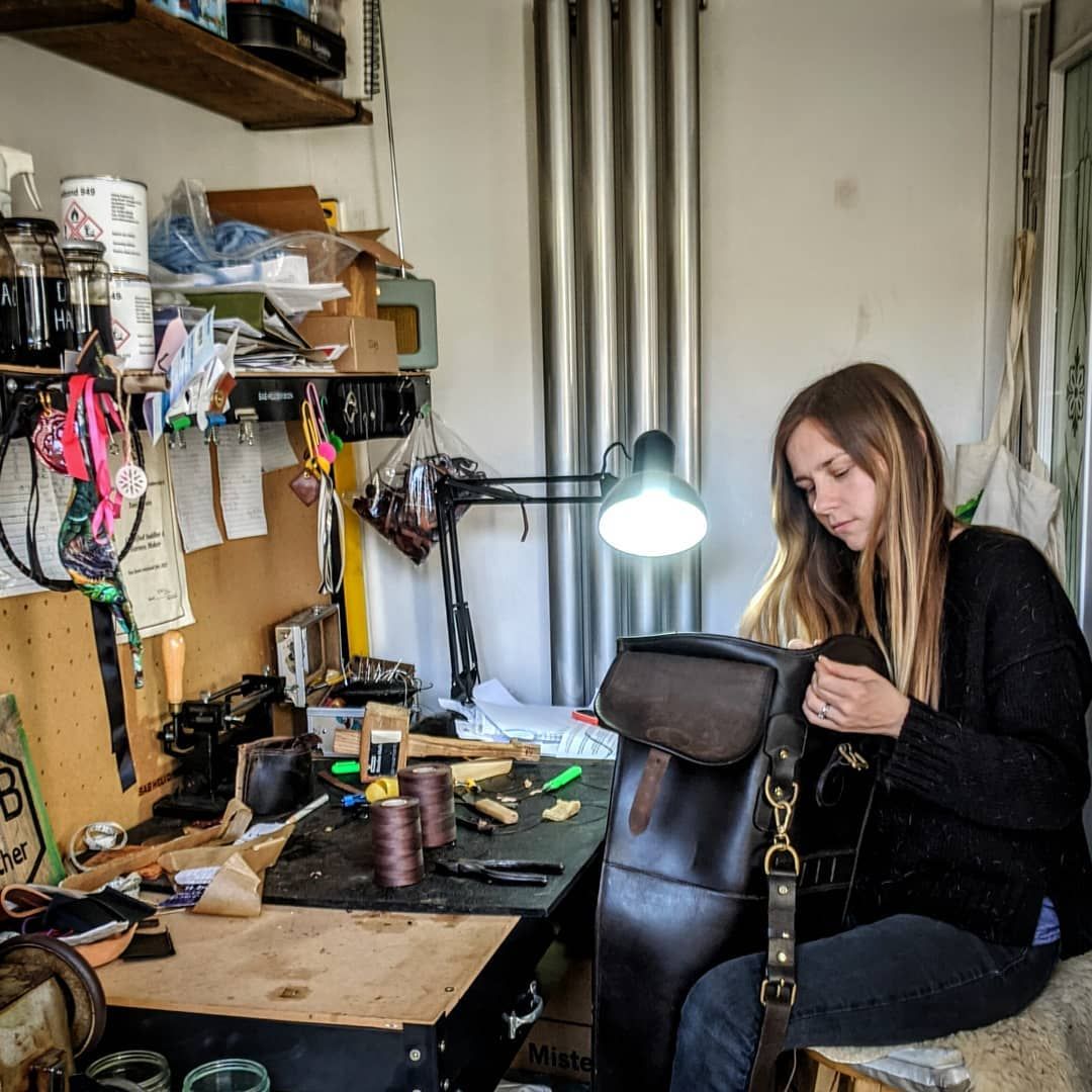 Tanis Brain, the saddler who repairs Rowdy bags in the UK, stitching leather at her workbench