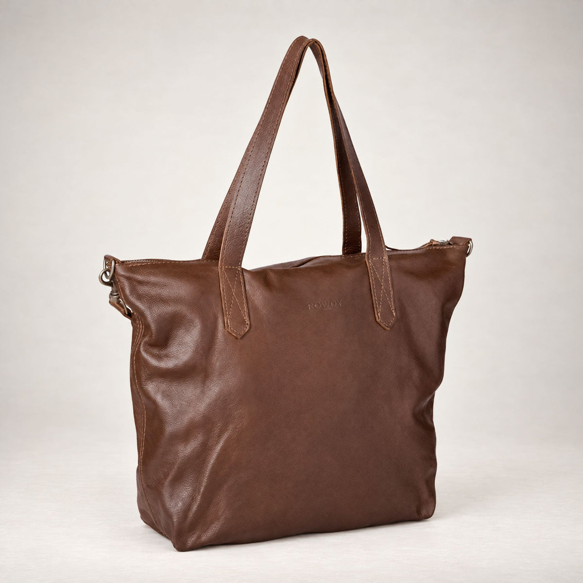 Rowdy Leather Crossbody Bag in Maple (smooth aniline leather), three-quarter view showing the zip top and grab handles