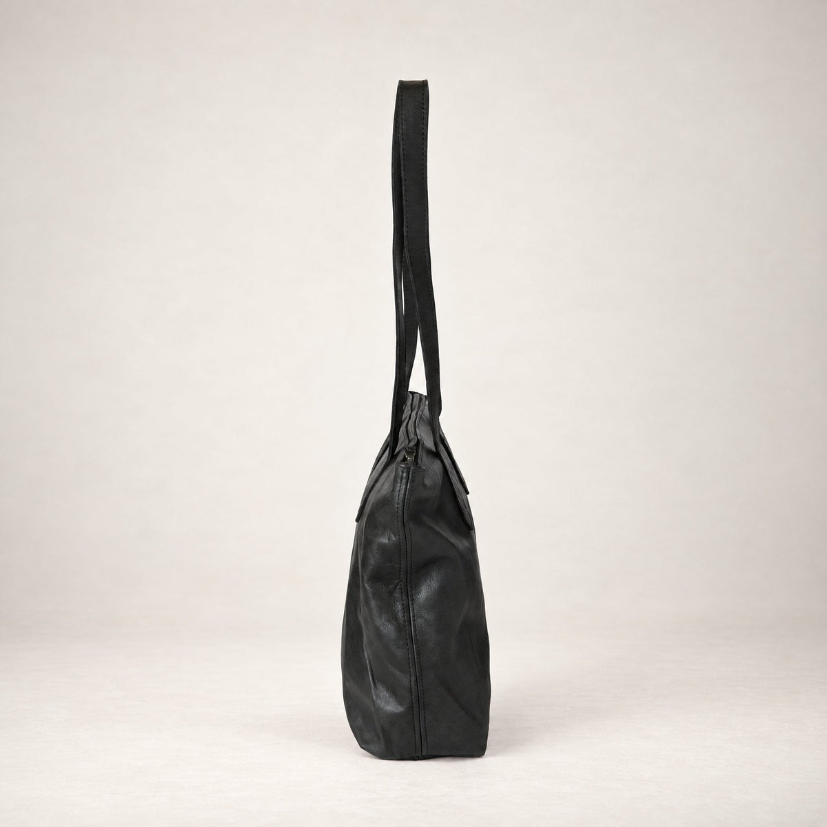 Rowdy Leather Tote Bag in Charcoal (textured aniline leather), side view showing its slim 12 cm depth