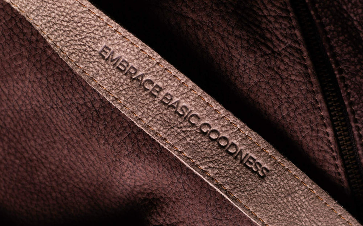 Close-up of a Rowdy full-grain leather strap embossed with the words Embrace basic goodness