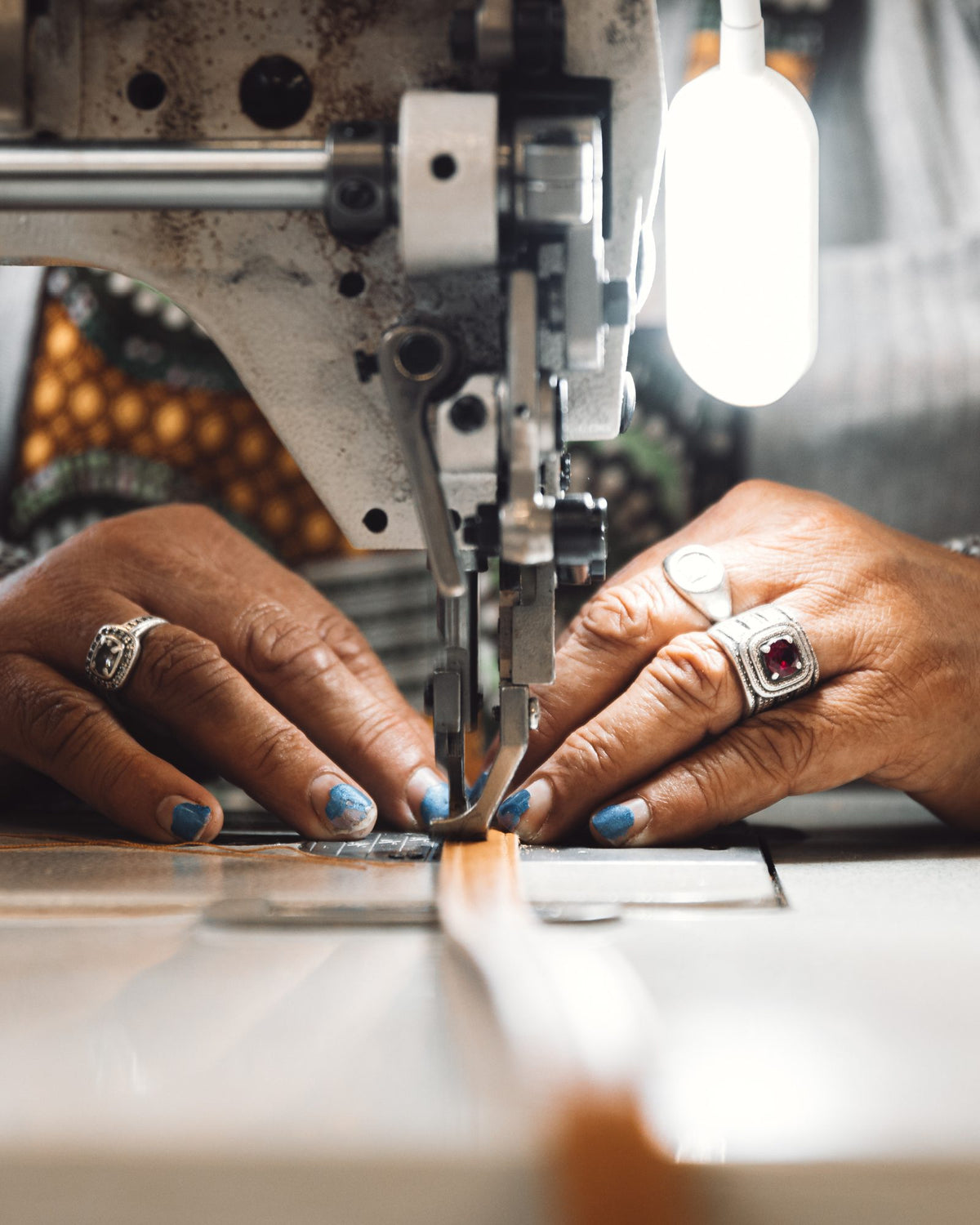 A maker's hands guiding leather through the sewing machine