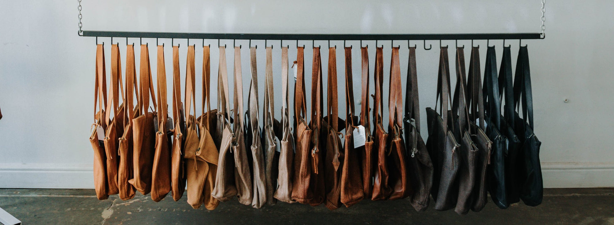 Rowdy leather bags hanging from a rail in every shade, from tan to charcoal