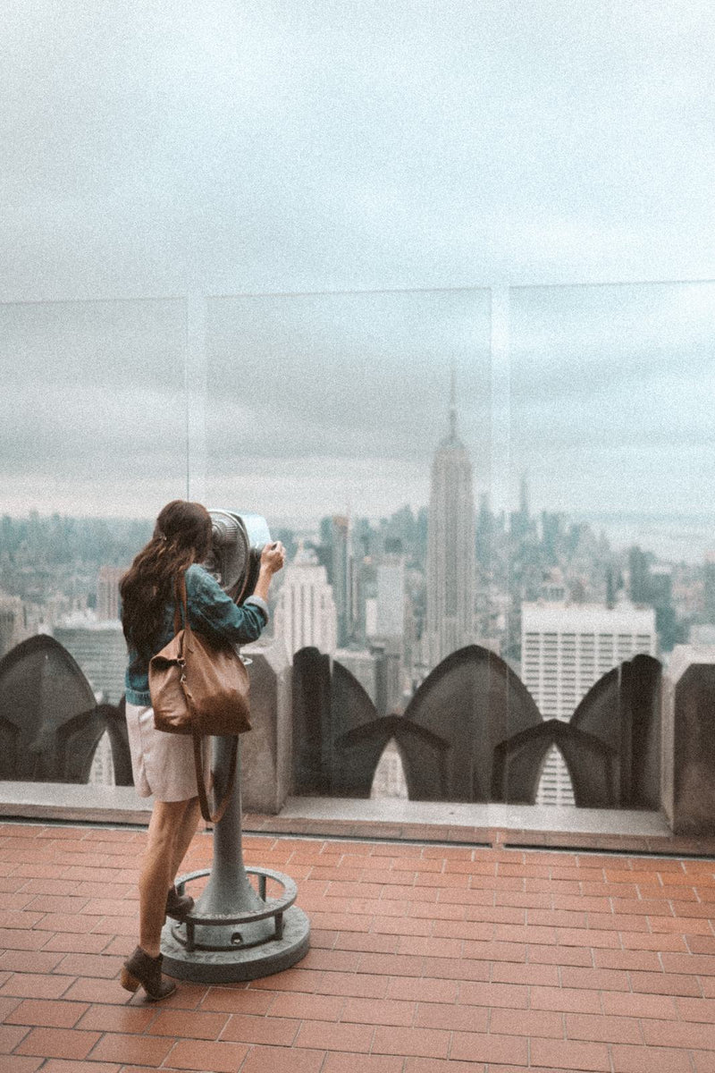 Woman in a denim jacket on a city rooftop with the Rowdy Leather Crossbody Bag on her shoulder