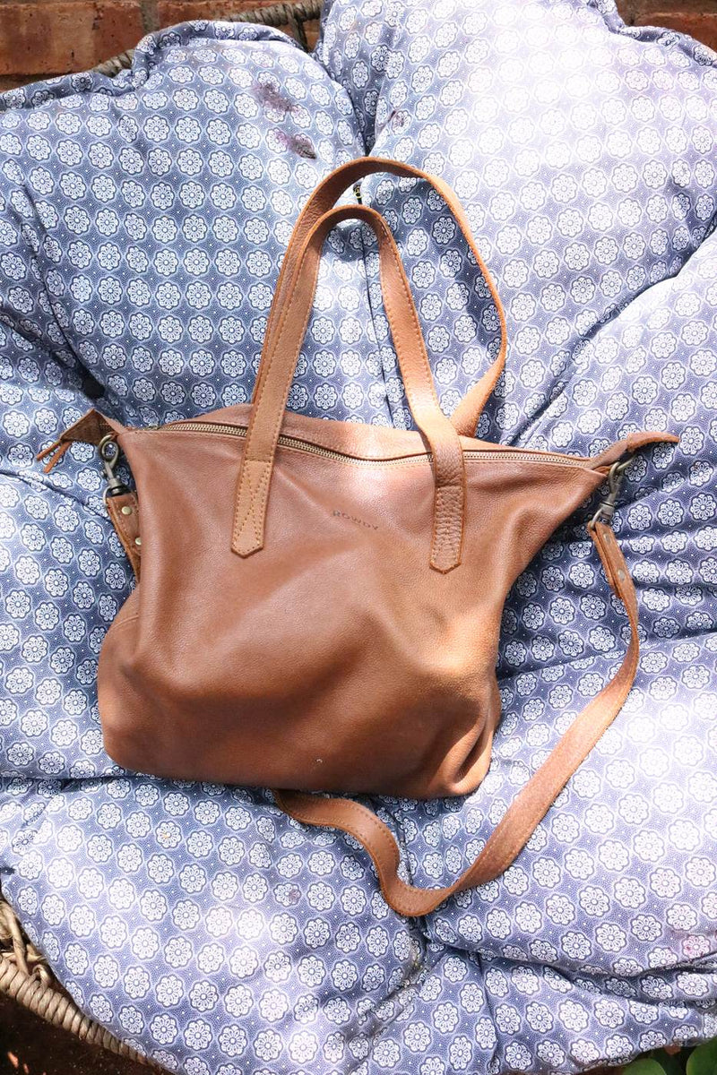 Rowdy Leather Crossbody Bag in Cedar resting on blue patterned cushions