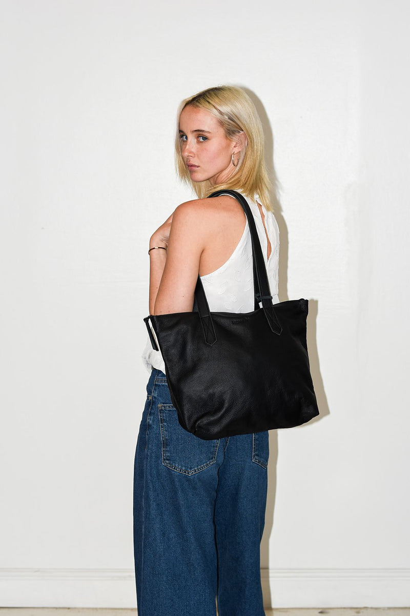 Woman in jeans wearing a black Rowdy Leather Tote Bag on her shoulder