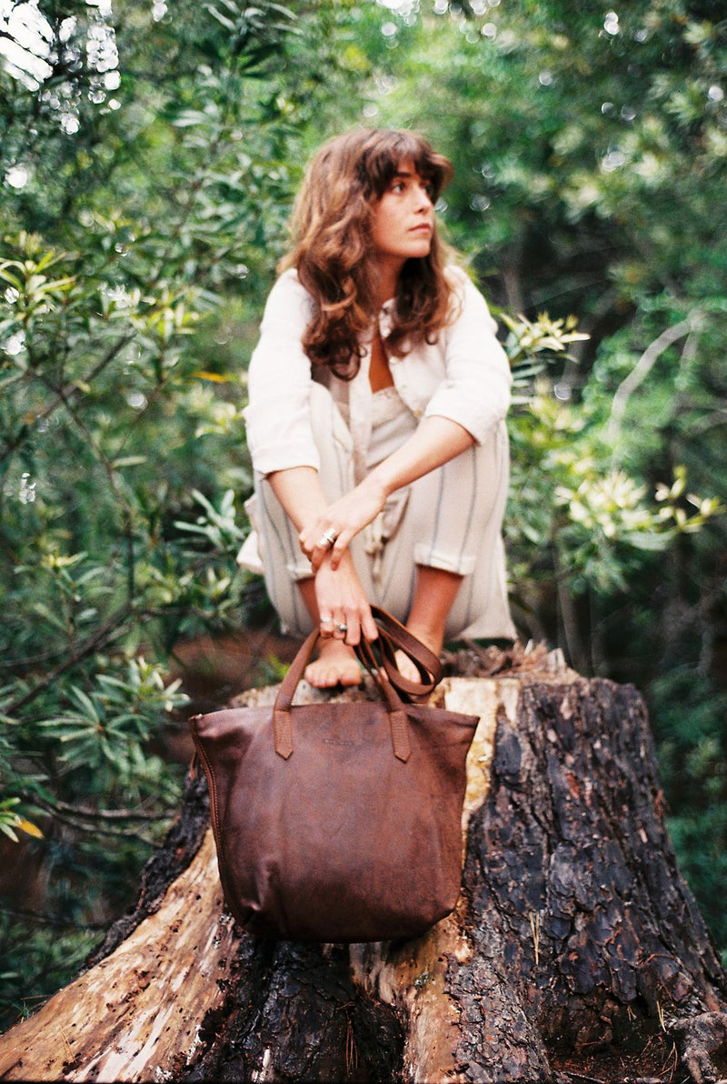 Woman in a forest holding the Rowdy Leather Tote Bag by its straps