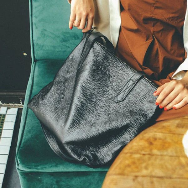Black Rowdy Leather Tote Bag on a green velvet seat